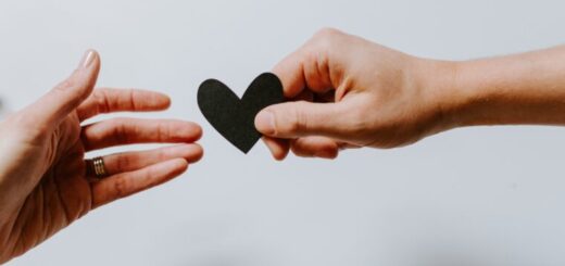 a hand holding a black heart description automati