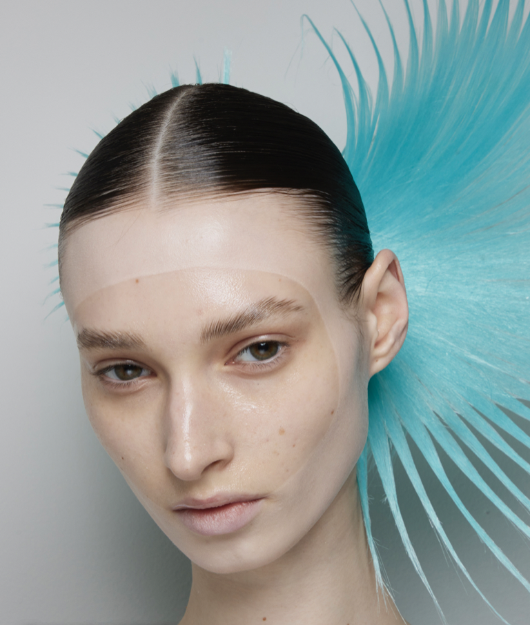 A person with a blue feathered hairDescription automatically generated