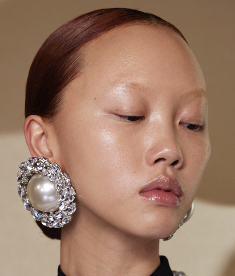 A person with a large pearl earringDescription automatically generated
