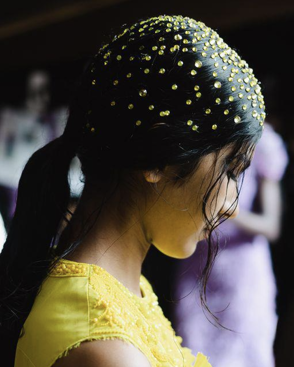 A person with a yellow dress and a yellow shirt with rhinestones on her headDescription automatically generated