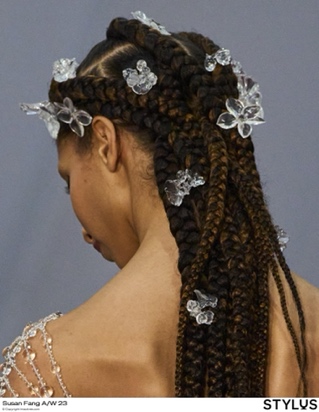 A person with braids and flowers in her hairDescription automatically generated