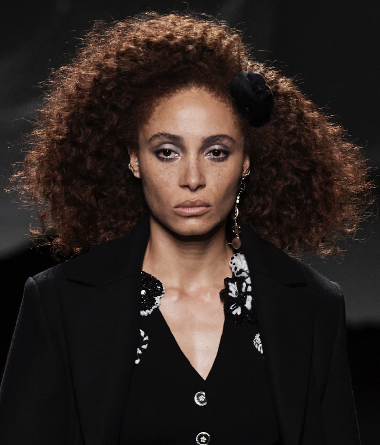 A person with curly hair wearing a black jacketDescription automatically generated