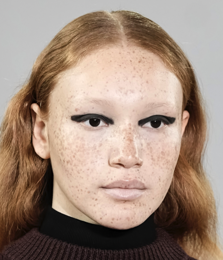 A person with freckles and black eyelinerDescription automatically generated