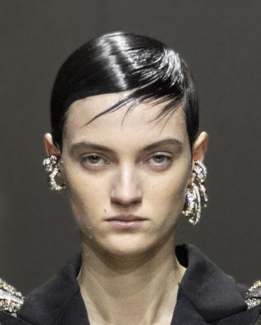 A person with short hair wearing earringsDescription automatically generated