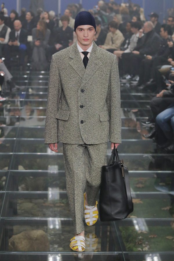 A person in a suit walking down a runway Description automatically generated