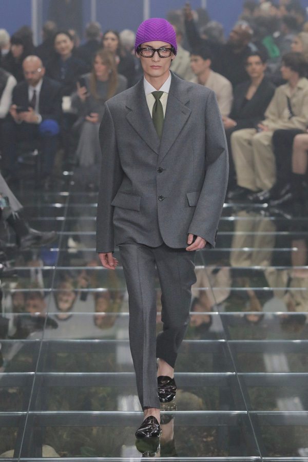 A person in a suit walking down a runway Description automatically generated