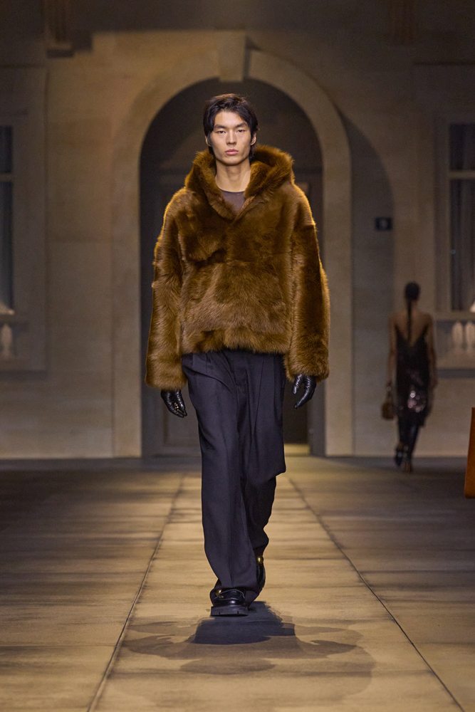A person wearing a fur coat and black pants Description automatically generated