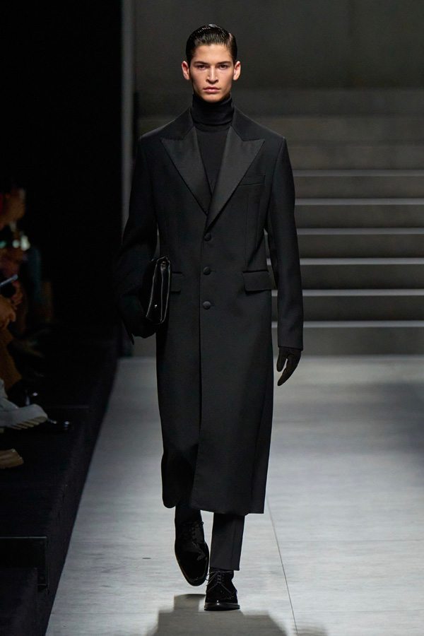 A person wearing a long black coat Description automatically generated